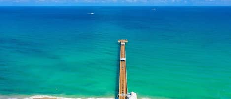 Une longue jetée qui s’avance dans l’océan, avec une plage à son extrémité.
