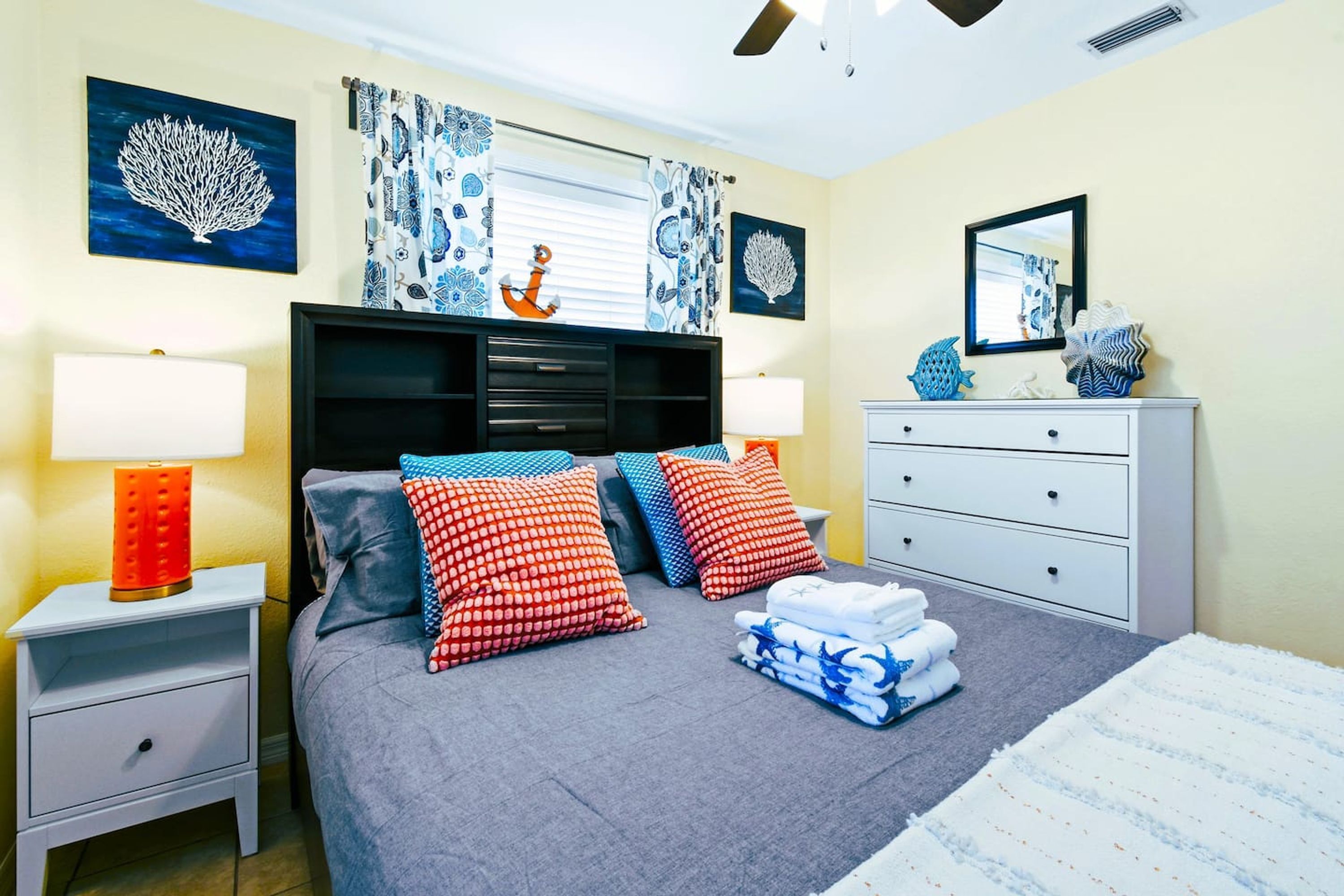 A neatly arranged bedroom with a bed, nightstands, a dresser, and decorative items.
