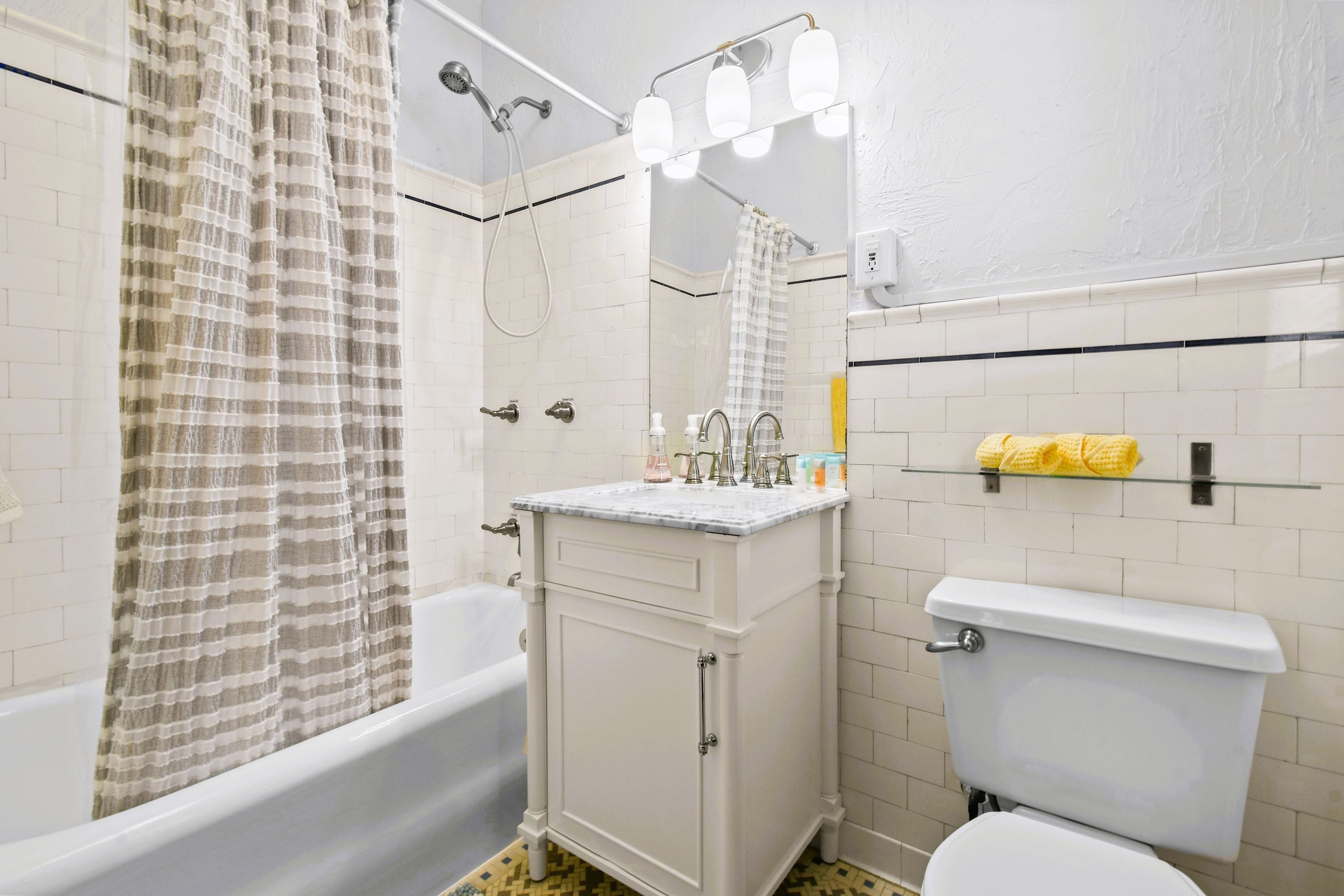 A bathroom with a bathtub, a toilet, a vanity with a mirror, and a shower with a curtain.