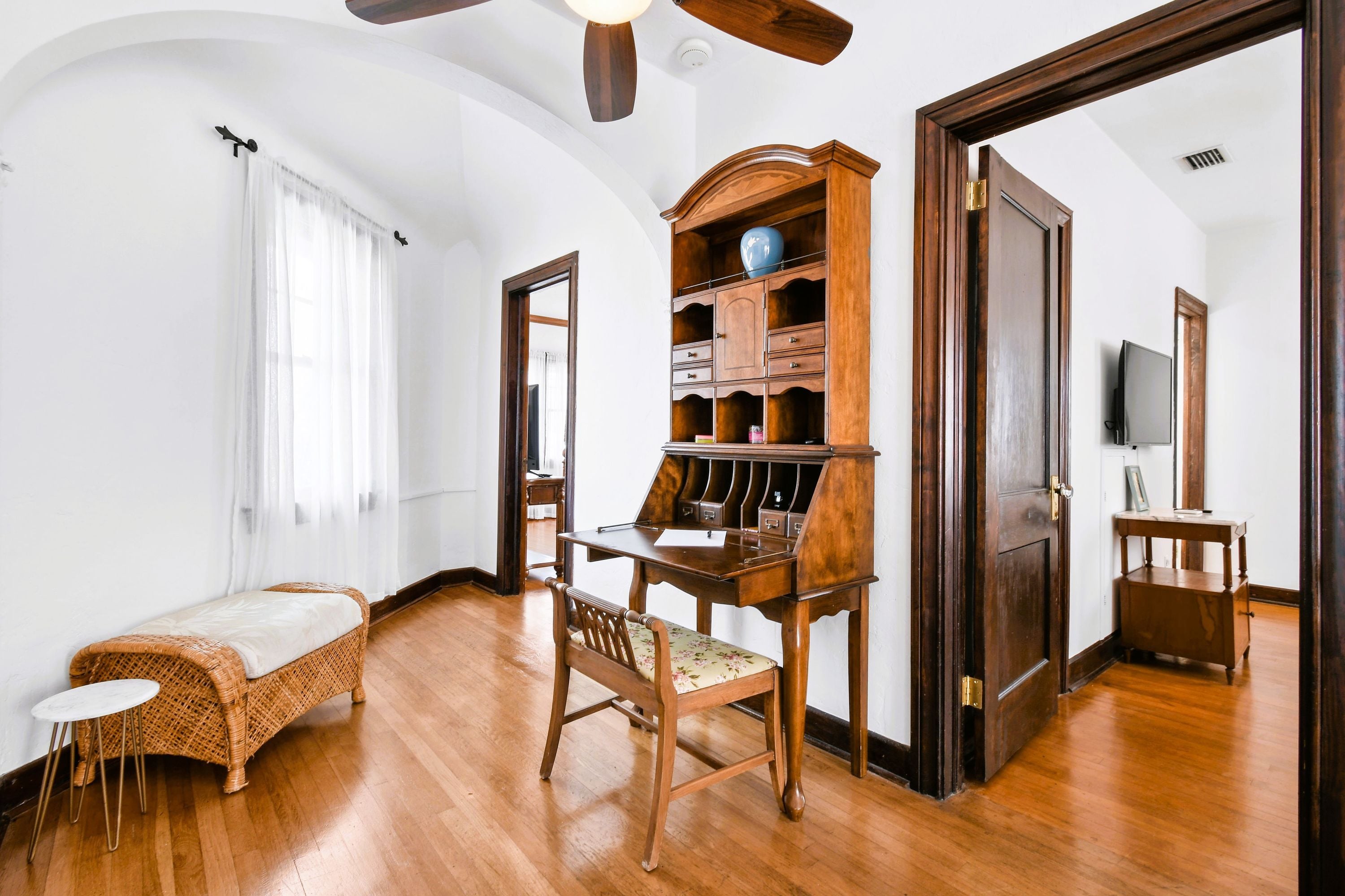 Une pièce comprenant un banc en bois, une petite table, un meuble en bois et un ventilateur de plafond.