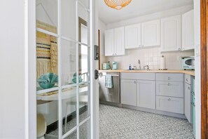 A kitchen with white cabinets, a stainless steel refrigerator, a coffee maker, and a vintage microwave. - 1926 Mediterranean Home With Heated Pool Sleeps 12 (West Palm Beach)