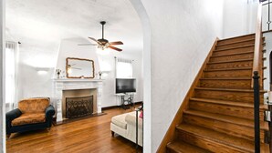 Un salon avec une cheminée, un canapé, un téléviseur et un escalier en bois.