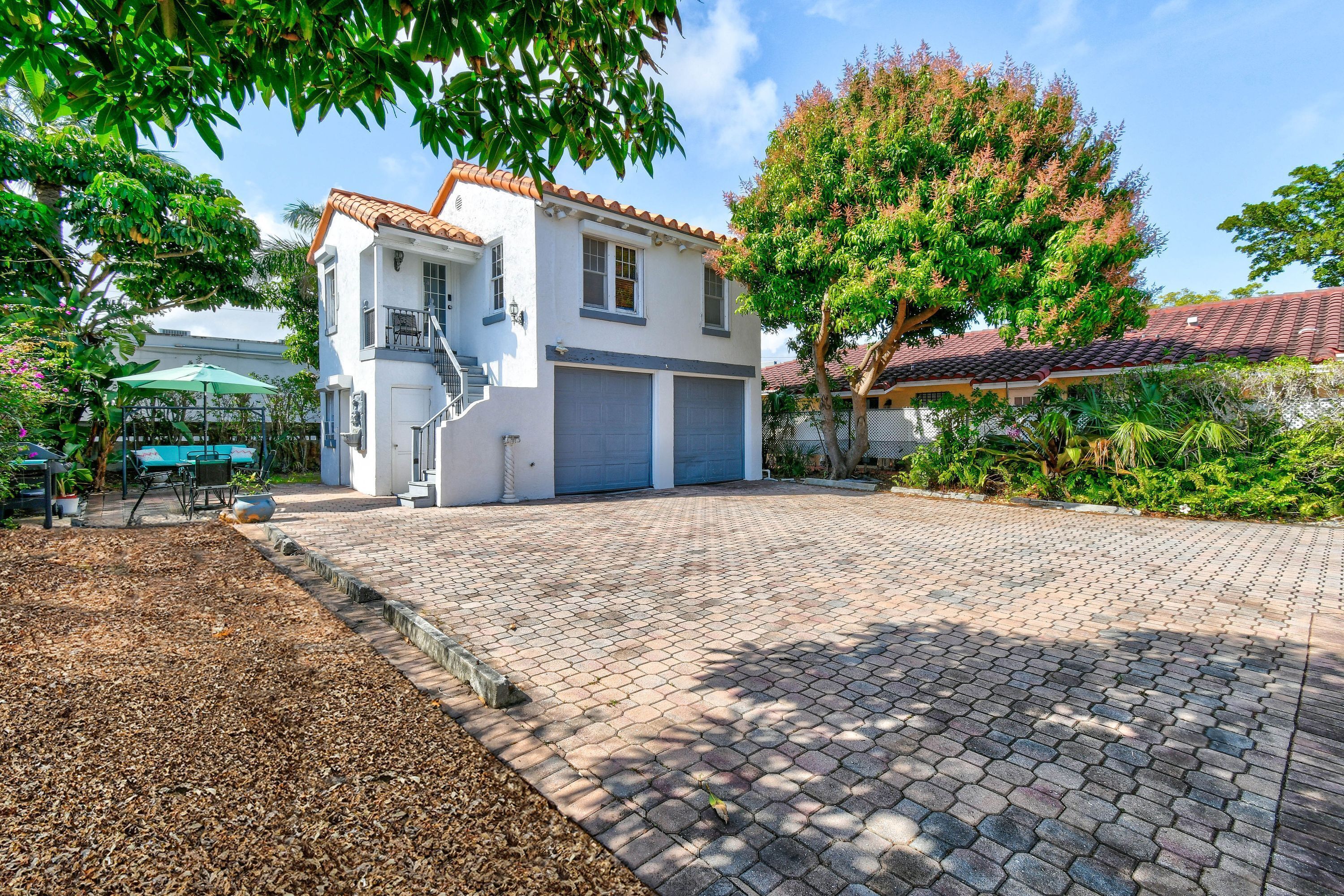 A two-story house with a tiled roof, a garage, and a paved driveway.