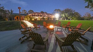 Un ciel étoilé, un foyer et des fauteuils Adirondack dans un coin aménagé en jardin.