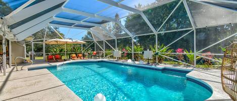 A covered swimming pool with a clear blue water, surrounded by a white frame and a blue canopy.
