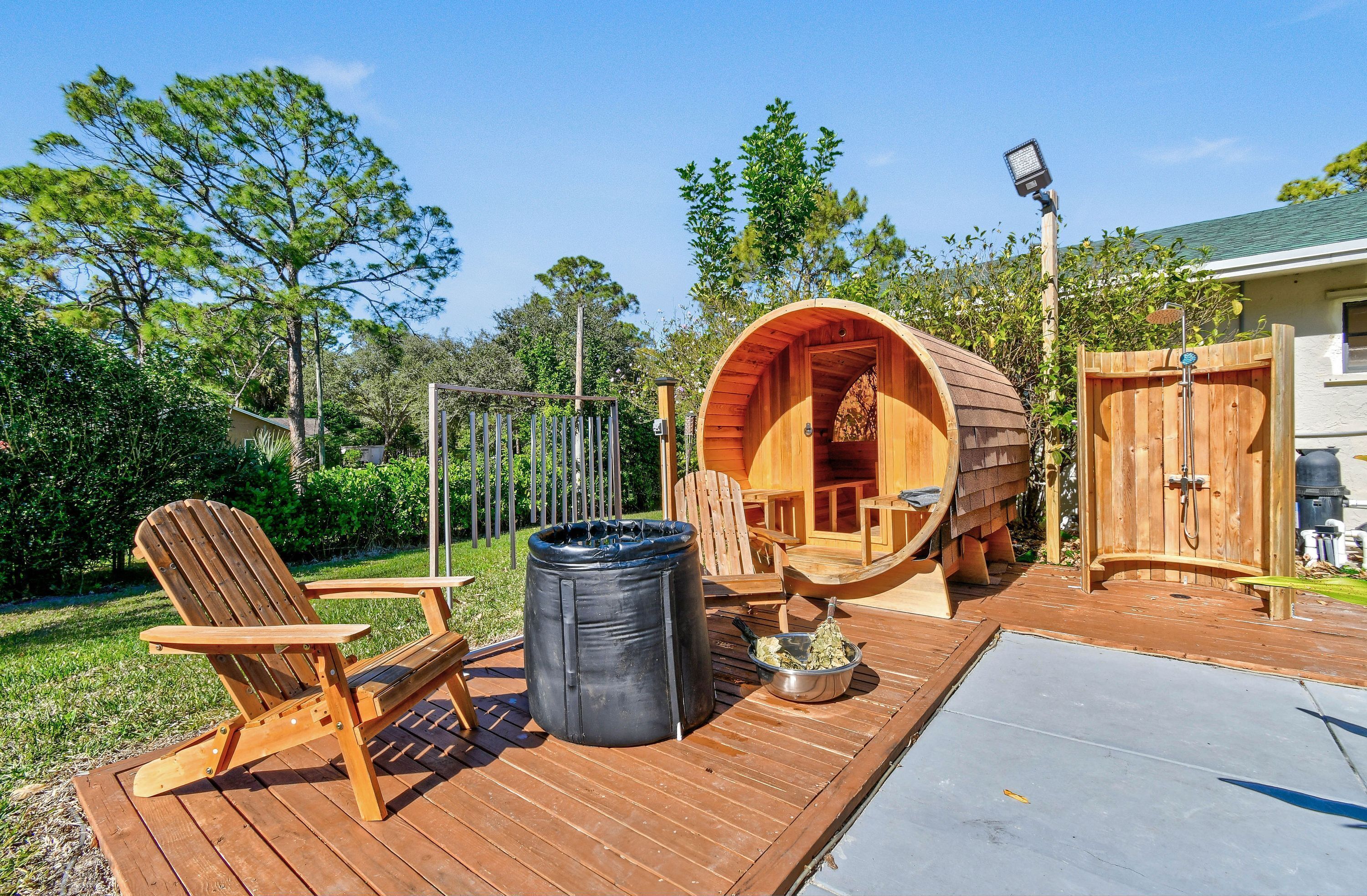A wooden deck with a hot tub, wooden chairs, and a wooden barrel structure.