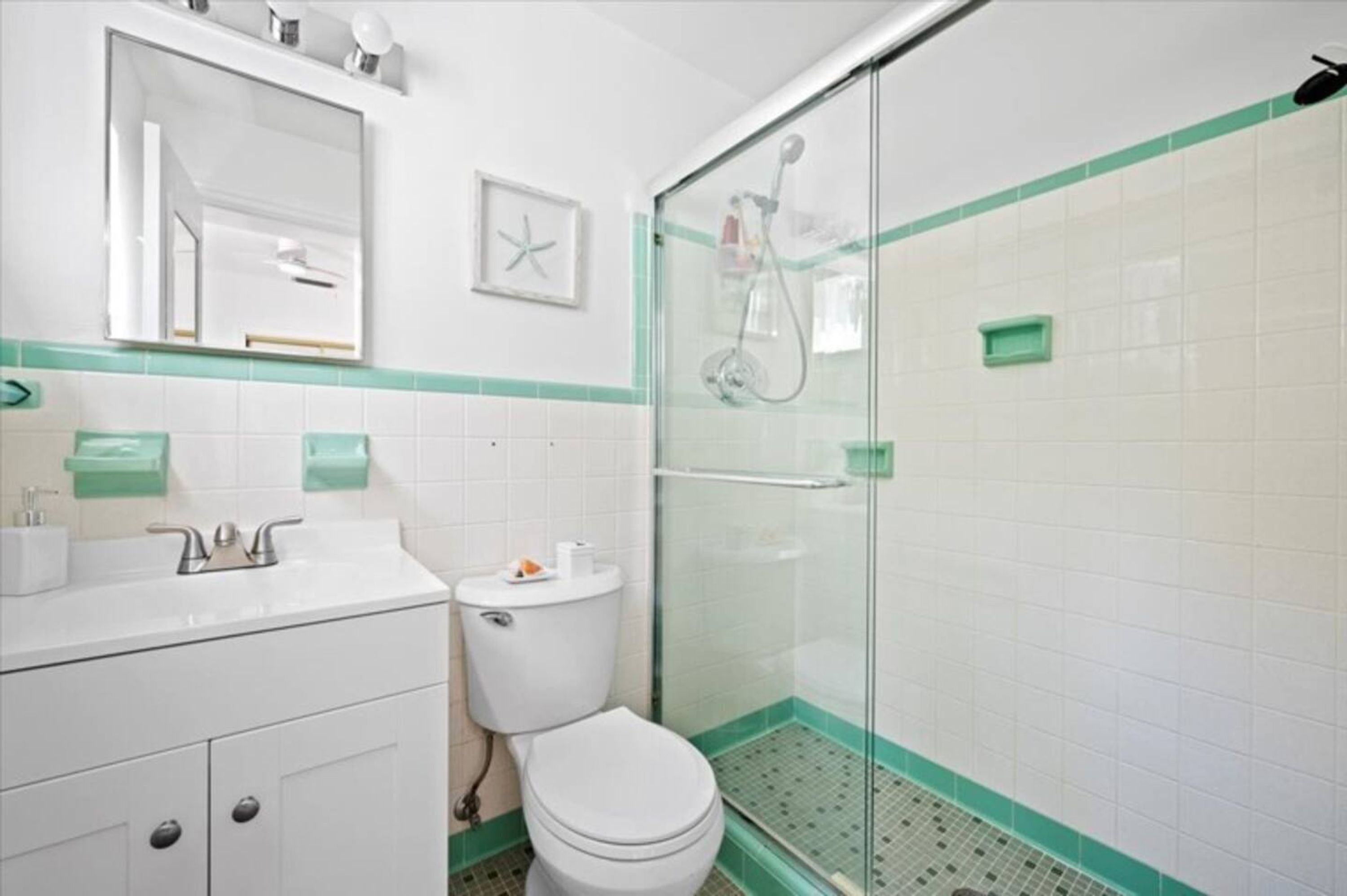 Une salle de bain équipée de toilettes, d’un lavabo et d’une douche à parois en verre.