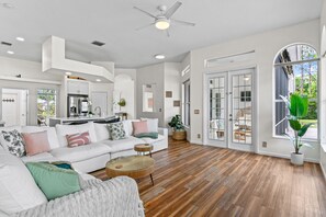 A spacious living room with a white sofa, a round coffee table, and a ceiling fan. - Why Is Everyone Obsessed With This House (Loxahatchee)