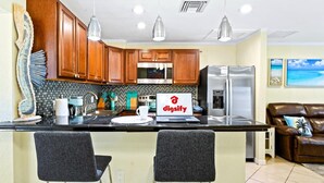 A modern kitchen with wooden cabinets, a stainless steel refrigerator, and a laptop on the counter. - NEW Home w Guest Suite Pool Near PGA Beach (Palm Beach Gardens)