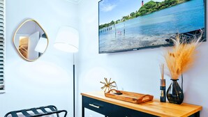 A modern room with a large window, a black and white desk, a mirror, a lamp, and a painting of a beach scene. - Luxury Sleeps 12 Kings Pool 2 Hot Tubs (Palm Beach Gardens)
