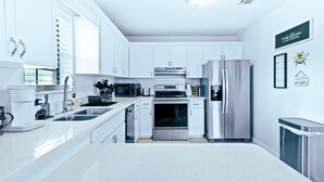 A modern kitchen with white cabinetry, stainless steel appliances, and a clean, minimalist design. - Luxury Sleeps 12 Kings Pool 2 Hot Tubs (Palm Beach Gardens)