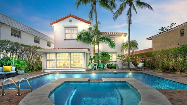 A swimming pool with a hot tub, surrounded by a patio area with outdoor furniture and palm trees. - 1926 Mediterranean Home With Heated Pool Sleeps 12 (West Palm Beach)