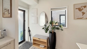 A modern interior with a wooden bench, a large black vase with a plant, a mirror, and a world map on the wall.