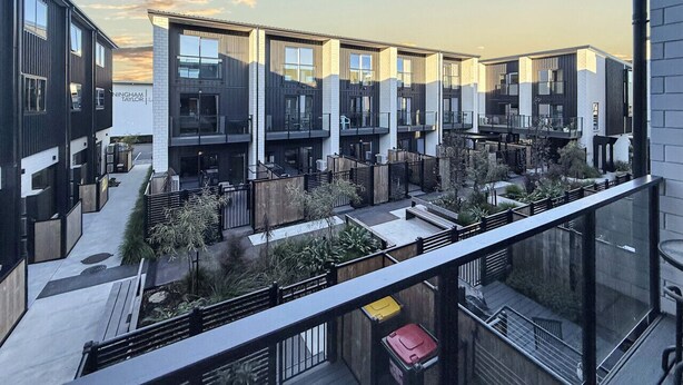 A modern building with multiple balconies and a rooftop garden.