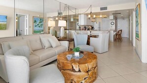 A modern living room with a sofa, coffee table, and dining area. - Beachfront 2BR condo in Marco Island with pool and WiFi. (Marco Island)