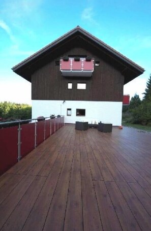 A building with a wooden deck, a red fence, and a small window. - Apartment '5' with Shared Terrace, Balcony and Wi-Fi (Dachsberg (Südschwarzwald))