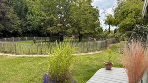 A wooden deck with potted plants, a fenced yard, and trees in the background. - Chalet with privacy and garden near Leeuwarden (Jelsum)