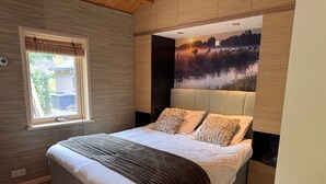 A modern bedroom with a large bed, a window, and a mural of a landscape. - Chalet with privacy and garden near Leeuwarden (Jelsum)