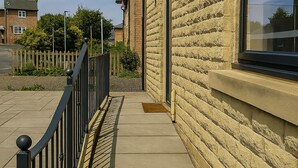 A concrete pathway beside a building with a brick facade and a black metal railing. - Elysian Residence (Newsome)