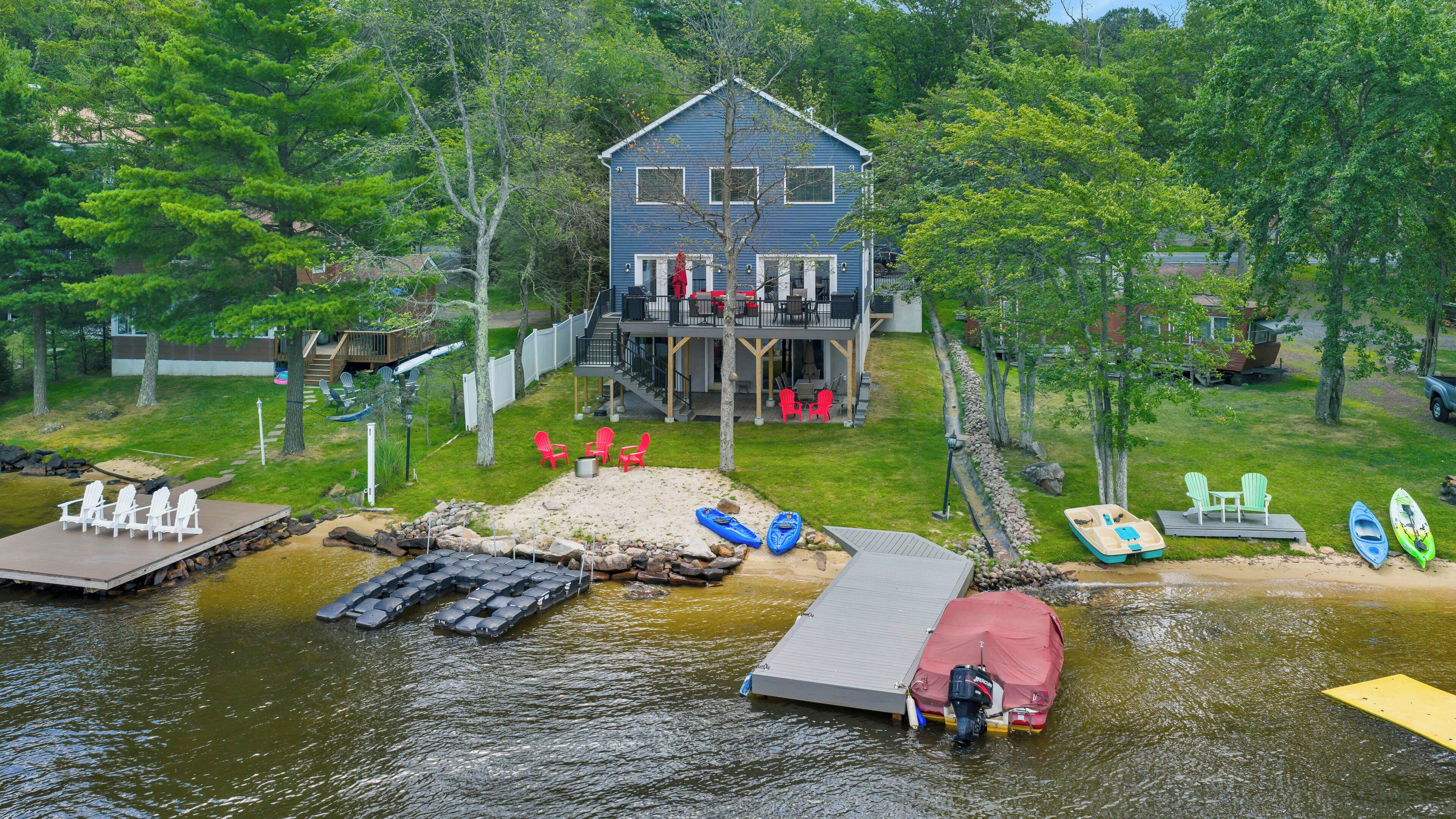 Una cabaña junto al lago con muelle, kayaks y mobiliario de exterior.