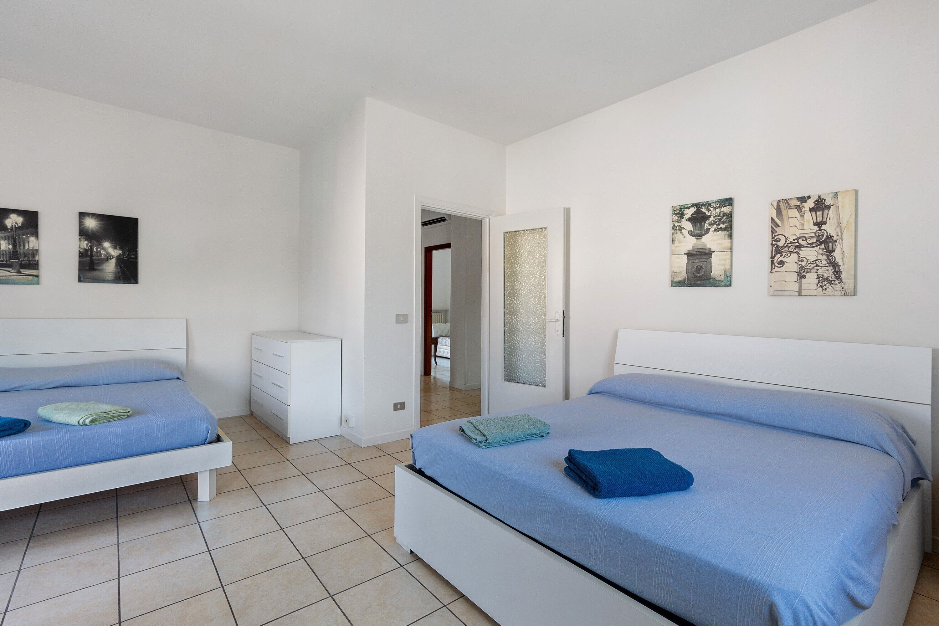 Ein Schlafzimmer mit zwei Betten, einer weißen Kommode und Bildern an den Wänden.