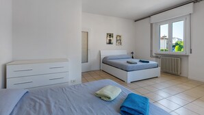 Un dormitorio con cama, cómoda, radiador y ventana con vistas.