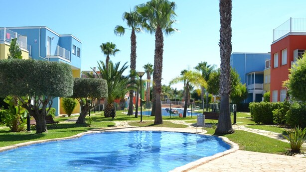 A swimming pool surrounded by palm trees and modern buildings.
