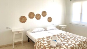 A bedroom with a bed, a nightstand, a wall-mounted decorative item, and a window.
