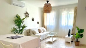 A room with a bed, a table, chairs, a TV, and decorative items.