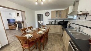 A modern kitchen with wooden cabinets, a black countertop, and a dining area with a wooden table and chairs. - Peaceful cottage with garden in Savonnières (Savonnières)