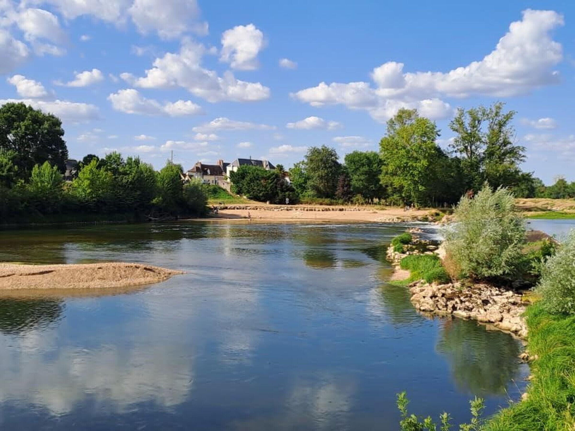 A serene riverside view with a house in the background.