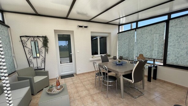 A modern dining area with a table and chairs, a decorative wall piece, and a door leading outside. - Peaceful cottage with garden in Savonnières (Savonnières)