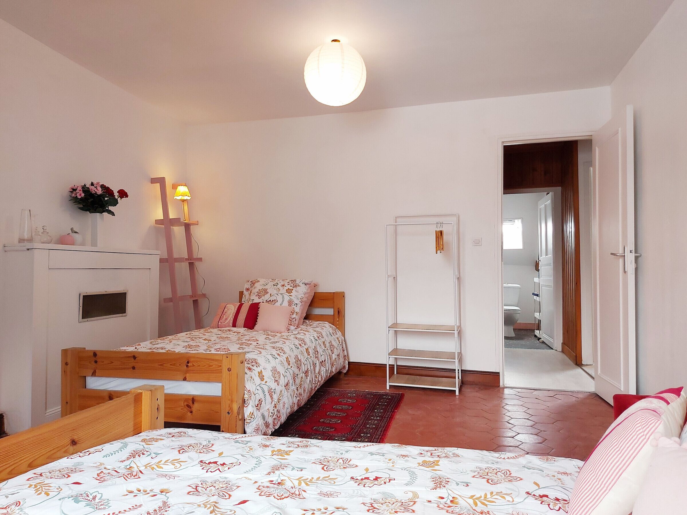 Quarto com cama de madeira, mesa de cabeceira com abajur, guarda-roupa e espelho.