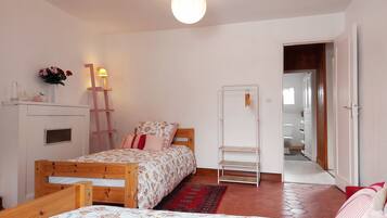 Quarto com cama de madeira, mesa de cabeceira com abajur, guarda-roupa e espelho.