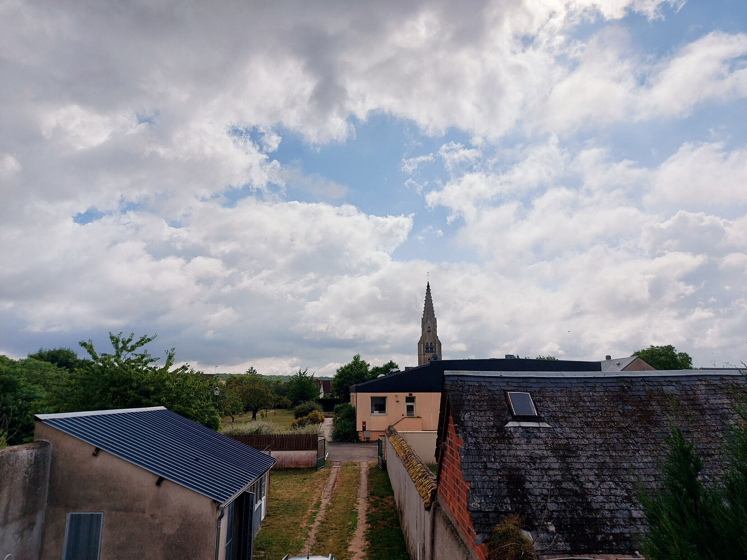 A residential area with a church tower, houses, and a solar panel on a roof.
