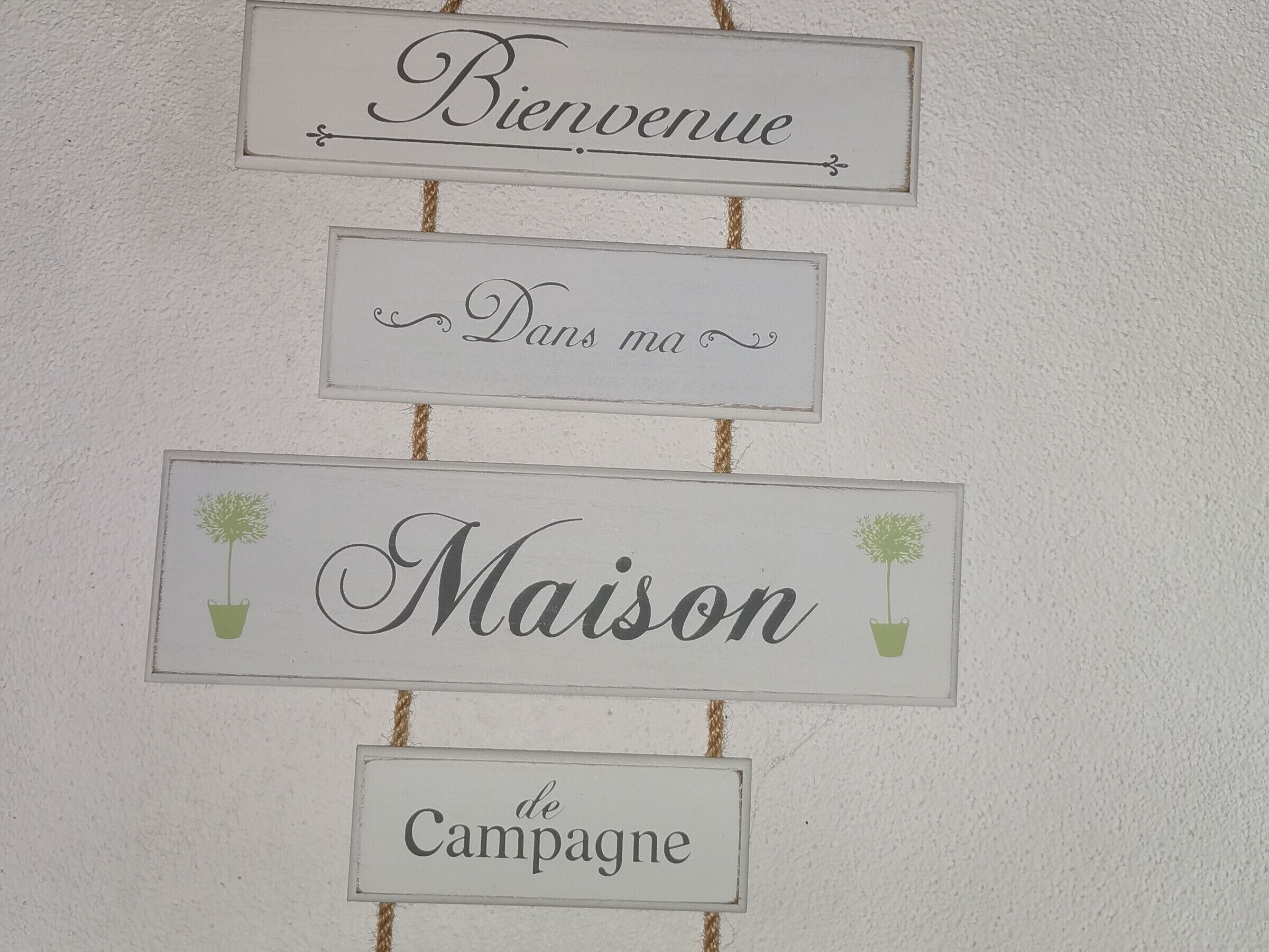 Un muro con tre cartelli: “Benvenuti”, “Nella mia” e “Casa di Campagna”.