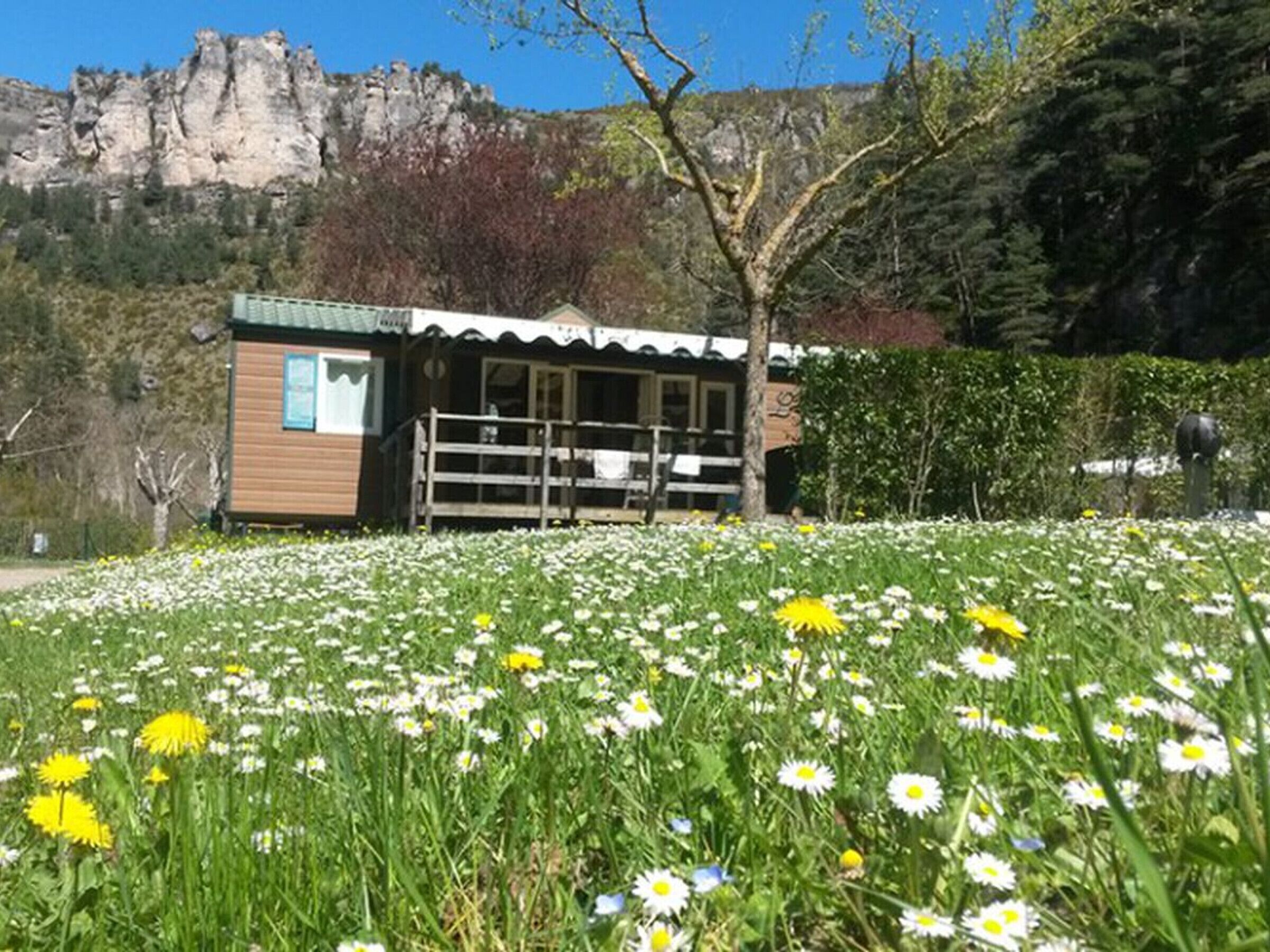 Una cabaña con fachada de madera, un porche y vistas a un paisaje montañoso.