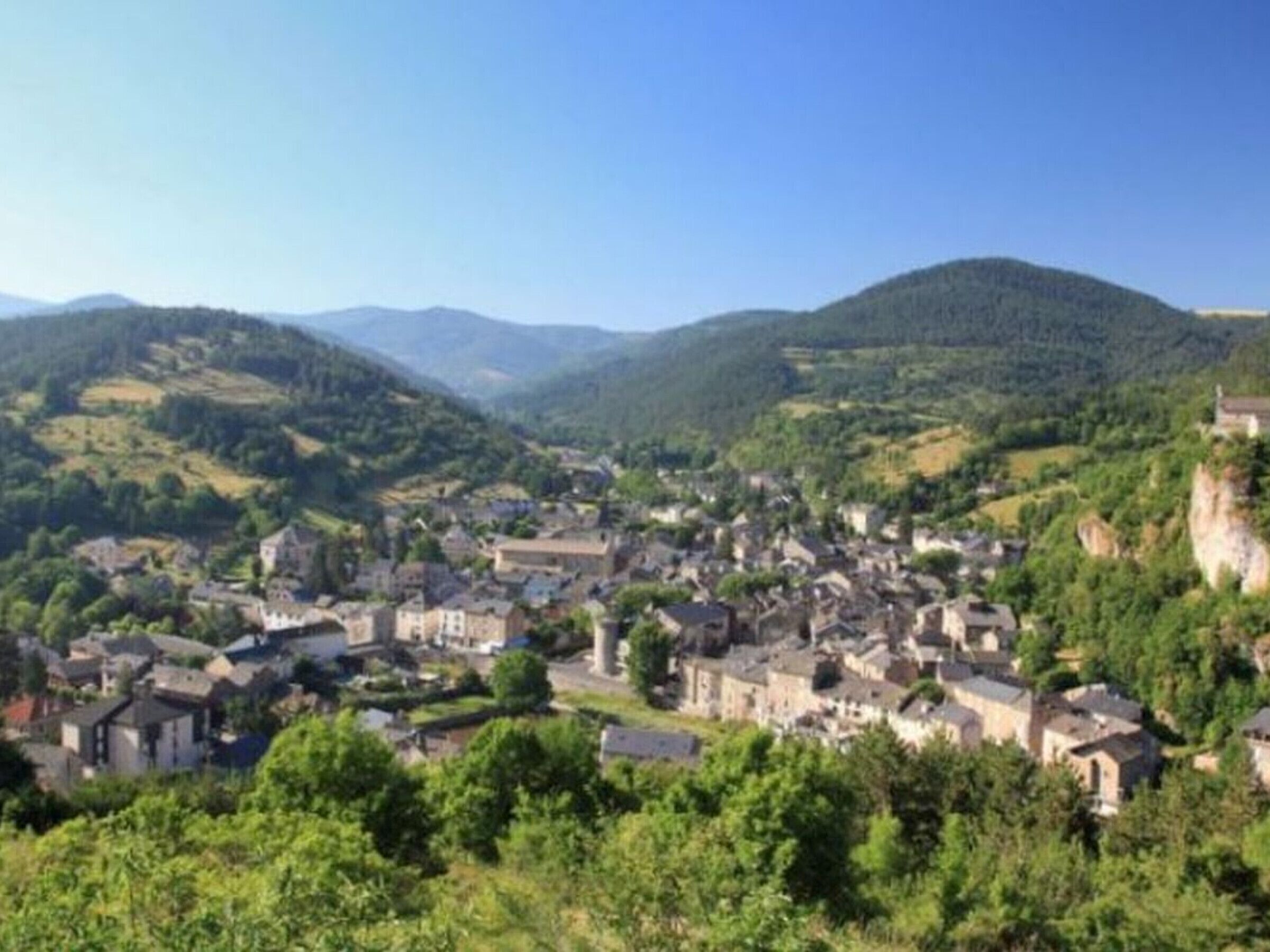 Eine Stadt eingebettet in ein Tal, umgeben von grünen Hügeln und Gebäuden.