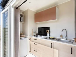 A modern kitchen with a built-in oven, microwave, and sink. There are cabinets and a countertop with various kitchen items.