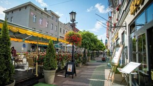 A street with outdoor seating, potted plants, and a signboard.