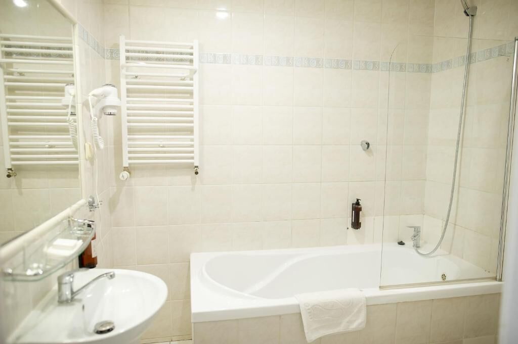 Un baño con bañera, lavamanos, espejo y ducha.