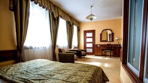 A hotel room with a large bed, a desk, a chair, and a mirror.