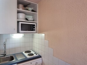 A compact kitchen with a microwave, a sink, and a stove.