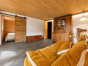 Ein Zimmer mit einem Bett, einem Holzschrank, einer Giraffenskulptur und einer Bank.