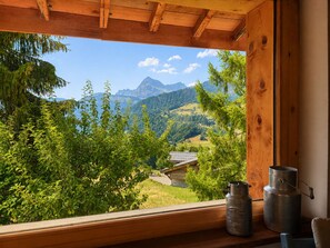 Eine Holzhütte mit einem Fenster auf eine gebirgige Landschaft.