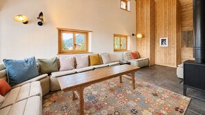 A cozy living room with a sofa, a wooden coffee table, and a fireplace.