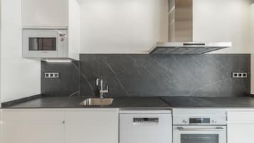 A modern kitchen with a Bosch microwave, dishwasher, and oven, a stainless steel sink, and a black marble backsplash.