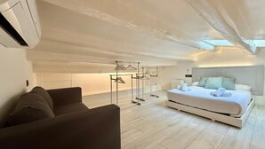 A modern bedroom with a large bed, a seating area, and a clothing rack. - Holiday Home 'El Racó Del Mas' with Private Terrace, Wi-Fi & Air Conditioning (Canet de Mar)