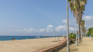 A beach with a stone wall, palm trees, and a volleyball net. - Holiday Home 'El Racó Del Mas' with Private Terrace, Wi-Fi & Air Conditioning (Canet de Mar)