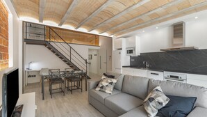 A modern living space with a staircase, a sofa, a dining area, and a kitchen. - Holiday Home 'El Racó Del Mas' with Private Terrace, Wi-Fi & Air Conditioning (Canet de Mar)